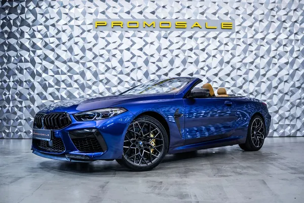 BMW M8 Competition Cabriolet Carbon en azul Marina Bay Blue con capota descapotable bajada, vista frontal lateral
